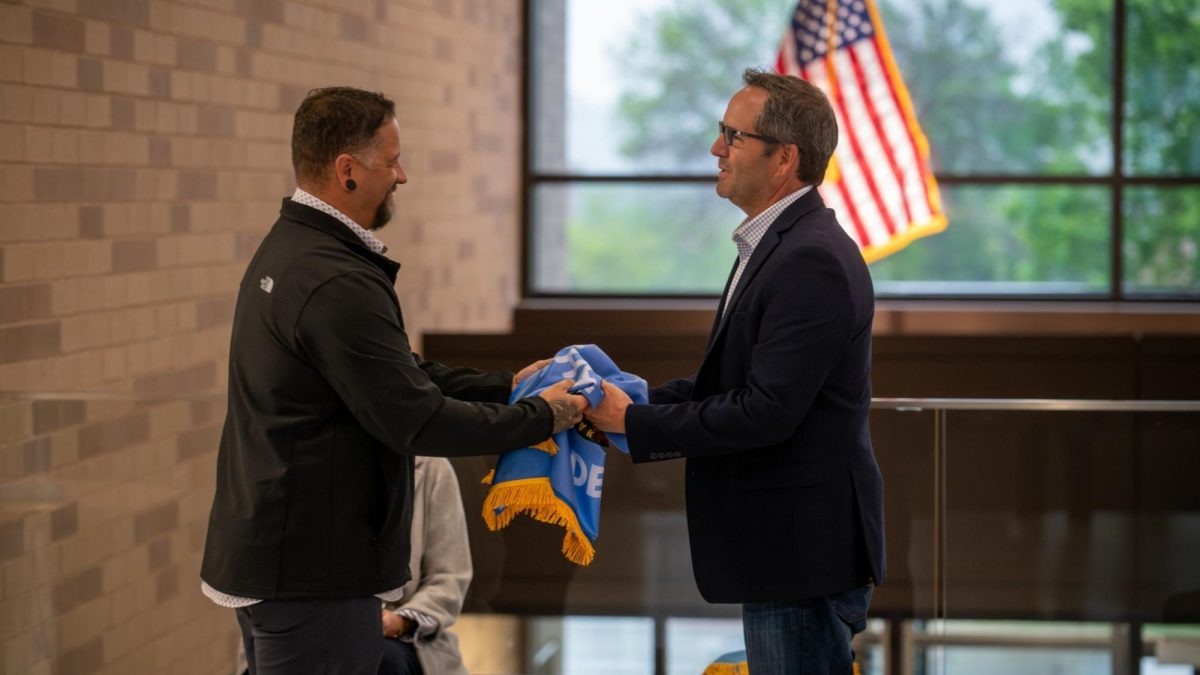 SMSC Chairman Cole Miller exchanges his community's flag with Dave Beer, chair of the Scott County Board.