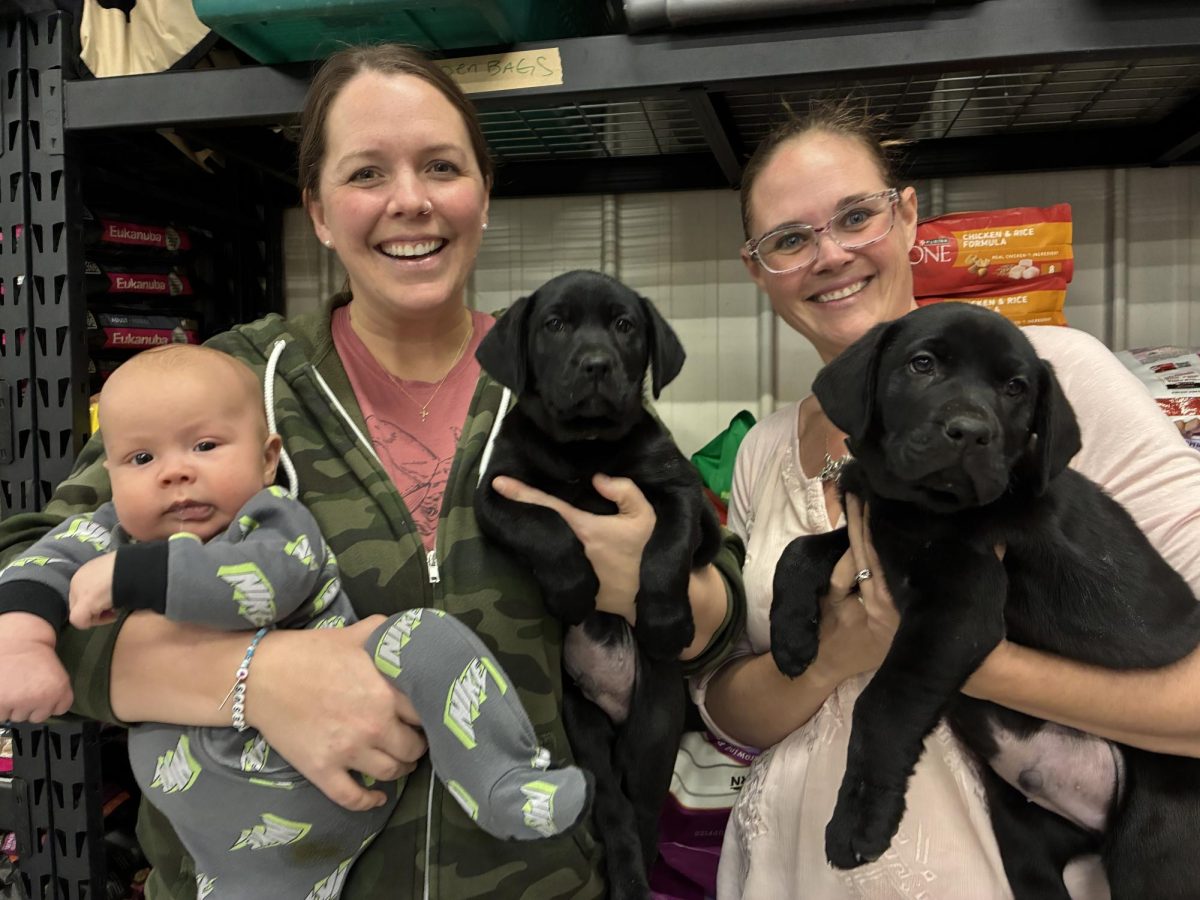 Casey Adams, director of Spot's Last Stop Canine Rescue, is joined by her young son, Wally, building manager Catie Leisure and two puppies that were recently put up for adoption.