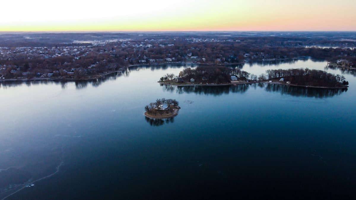 An aerial view of an ice-covered lake in a city, with houses on islands and ringing the shore.